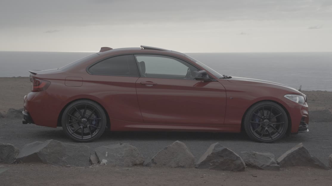 El coche sin etalonar, en S-Log3. La carrocería roja sale apagada, casi teja, el cielo y el mar se funden en un gris plano y los neumáticos no se separan del asfalto.